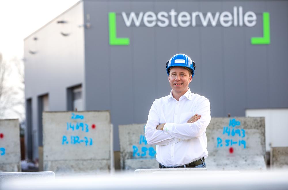 [Translate to Polski:] Portrait des geschäftsführers mit Hel vor dem Gebäude mit dem Schriftzug westerwelle