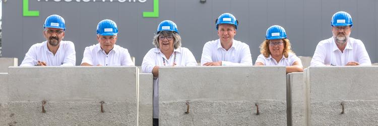 [Translate to Polski:] Sechs Mitarbeiter/innen mit Helmen hinter Winkelstützen